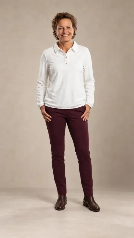 Vrouw in een wit poloshirt en een slanke bordeauxrode stretch pantalon met elastische band van Sensia